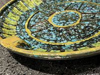 Close-up view showing the detailed lava glaze texture and coloration in blue and green with yellow accents.