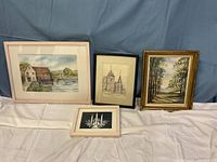 Four artworks displayed framed with matting on a table against a blue backdrop, including landscapes and sketch signed by Rosemary Taylor