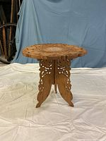 Full view of carved round wooden table showing top and base details from a side angle