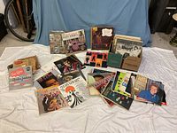 Wide view of approximately two dozen vinyl records laid on cloth, shows mixed genres and album cover art