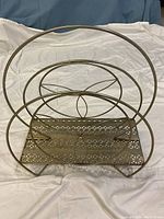 Front angle showing round atomic style metal frame and perforated base for magazine storage.