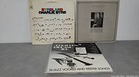 Five vinyl album covers including Charlie Byrd 'Byrdland' on left, Duke Ellington on right, jazz compilation in front.