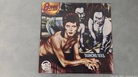 Front cover of David Bowie Diamond Dogs vinyl LP album showing artwork of Bowie and two creatures, with 'Bowie' and 'Diamond Dogs' text.