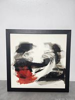 Full view of framed abstract art print with prominent black, red, and white brush strokes.