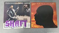 Two Isaac Hayes LP vinyl albums side-by-side, the SHAFT soundtrack double album and For The Sake of Love, showing both front covers.