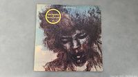 Front cover of The Cry of Love album showing a portrait sketch of Jimi Hendrix with a gold circular sticker.