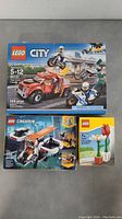 Photo showing all three sealed LEGO sets together on floor including Tow Truck 60137, Drone Explorer 31071, and Building Toy 40187 boxes