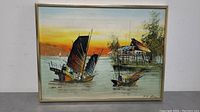 Framed painting showing two traditional Chinese boats and a stilt house at sunset, signed by P.T. Lam.