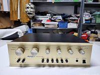 Front view of gold anodized aluminum faceplate showing control knobs, input selector, headphone jack and power switch.
