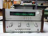 Front view of HEATHKIT AA-1219 amplifier and AJ-1219 tuner showing control knobs, buttons, and tuning dial on metal front panels with wood sides.