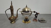Photo showing full lot with all 4 items: brass teapot, Sputnik barometer, discus thrower statuette, and pewter RCMP car.