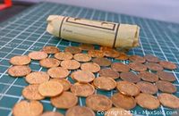 Coins scattered with a rolled coin wrapper in the background, showing copper color and circulation wear
