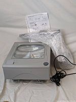 3M 1700 overhead projector unit with large fresnel lens and attached power cord. Projector arm wrapped in bubble wrap and instruction sheet included at back.