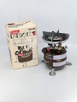 Photo of Coleman Peak 1 stove alongside original packaging box showing the stove and box in upright position.