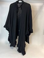 Black shawl hanging to show full length and ruffled edge detail.
