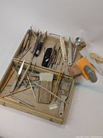 Overall view of wooden box with ceramic clay sculpting tools showing a variety of wooden-handled tools, brushes, and plastic scrapers.