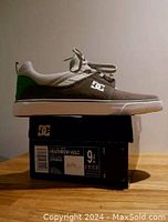 Side view of the grey DC Heathrow Vulc skateboarding shoe resting on its original box, showing the overall color and construction.