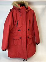Front view of the red women's winter jacket with fur hood, showing zippered chest pockets and button flap pockets at the bottom.