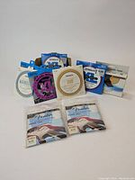 Eight sets of various new guitar and mandolin string packages displayed together showing brand and model details.