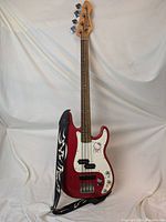 Full view of the red electric bass guitar with Hello Kitty decals and the attached black and white tribal pattern Levy's guitar strap.