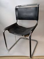 Front and side angle of chair showing chrome tubular frame, black leather back in good condition, and the damaged black leather seat sagging and torn.