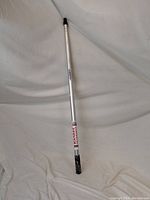 Full length view of the silver aluminum telescoping pole standing against a white background showing its overall condition and length.