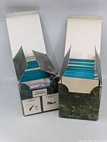 Two open boxes containing sets of warplane collector cards with visible blue-backed cards inside.