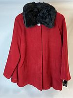 Full front view of the red winter coat with black faux fur trim collar and two side pockets. The coat has a built-in cape and buttons up the front.