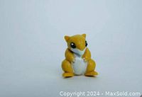 Front view of small yellow and white Sandshrew figure with large black eyes and sculpted details.