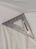 Full view of the triangular metal Swanson Speed Big 12 Speed Square showing all measurement markings and overall condition.