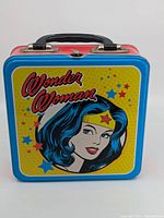 Front view of Wonder Woman lunchbox showing yellow front panel with red Wonder Woman logo and illustrated portrait.