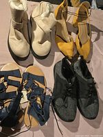 All four pairs displayed together: beige furry boots, yellow ankle-tie heels, blue sandals, black sneakers.