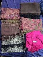 Overview of six scarves stacked, showing a variety of colors and patterns including a bright pink pashmina labeled Estavana.