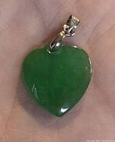 Close-up front view of the heart-shaped green stone pendant with silver bail.