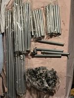 Photo showing various metal rods bundled and several plastic connectors in plastic bags arranged on a surface.