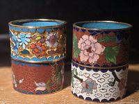 Two pairs of colorful floral cloisonné napkin rings on a wooden surface, showcasing both their exterior and interior designs.
