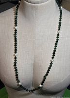 Front view showing full length of necklace with green stone beads and spaced white pearls