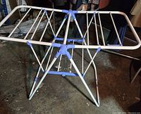 Foldable laundry drying rack fully opened and set up, showing the top drying surface and supporting base.