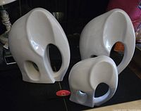 Three white ceramic elephant sculptures of varying sizes on a dark surface