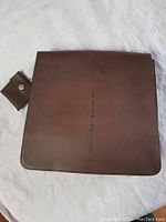 Front view of brown leather purse with embossed 'Ssamzie' branding and attached pouch with snap closure.