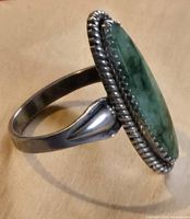 Side view of the sterling silver ring with elongated oval green jade stone set in twisted rope bezel.