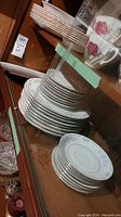 Stack of dinner plates, side plates, saucers with floral and silver rim pattern, visible crazing on plates