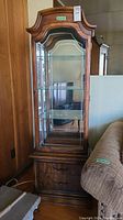 Front view of wood and glass curio cabinet with glass door and wood base with two drawers.
