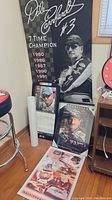 Full view showing large laminated hanging fabric banner poster with Dale Earnhardt Jr. image and 7-time champion years. The framed 2013 calendar and other memorabilia are positioned on floor and table.
