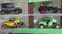 Four diecast model cars on display, featuring black, tan, yellow, and green colored Fords with detailed wheels and realistic parts.