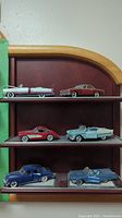 Full view of all six Franklin Mint diecast cars arranged on display shelves, showcasing their distinct vintage American car designs and colors.