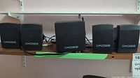 Five Koss branded components on a shelf: one amplifier and four speakers with cables attached.