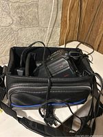 Panasonic PV-L459 video camera placed in a padded black carrying bag with charger and cords inside, showing condition and accessories included.