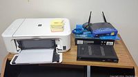 Photo of Canon Pixma MG3520 printer scanner, Linksys wireless router with two antennas, and Arris Shaw Direct receiver on wood table