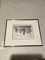 Framed monochrome print of four wolves in snowy forest titled 'Wolfpack in Snowstorm' with artist signature visible.